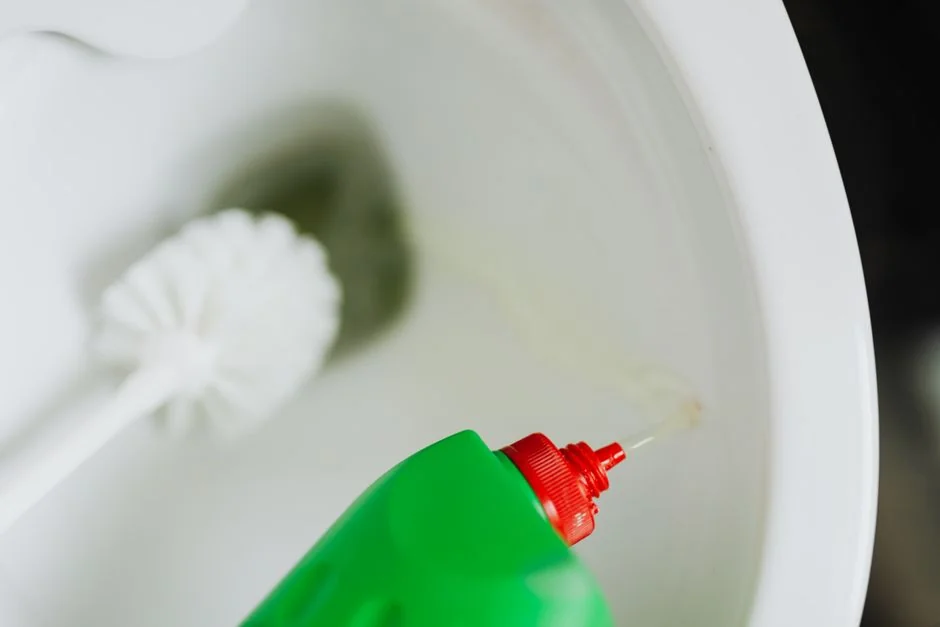 who-we-are Individual in protective equipment sanitizing a bathroom sink with a spray bottle.